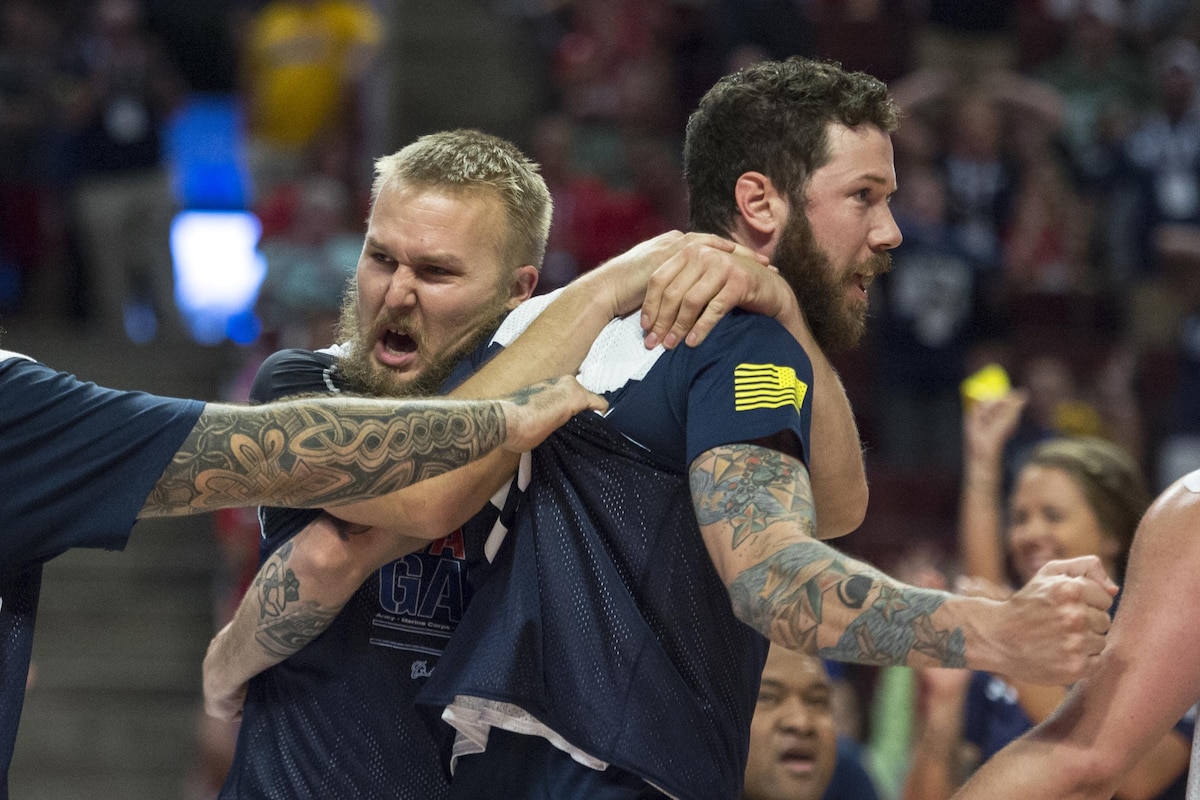 Two Navy veterans celebrate winning gold in sitting volleyball.