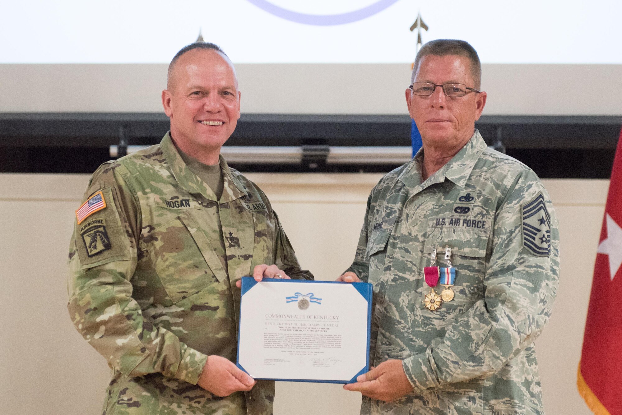 Chief Master Sgt. Jeffrey Moore (right), the outgoing state command chief master sergeant, receives the Distinguished Service Medal from Army Maj. Gen. Stephen Hogan (left), the adjutant general for Kentucky, during Moore’s retirement ceremony at the Kentucky Air National Guard base in Louisville, Ky., on May 20, 2017. Moore is retiring after 35 of service to the Kentucky Air National Guard and United States Air Force. (U.S.  Air National Guard photo by Staff Sgt. Joshua Horton)