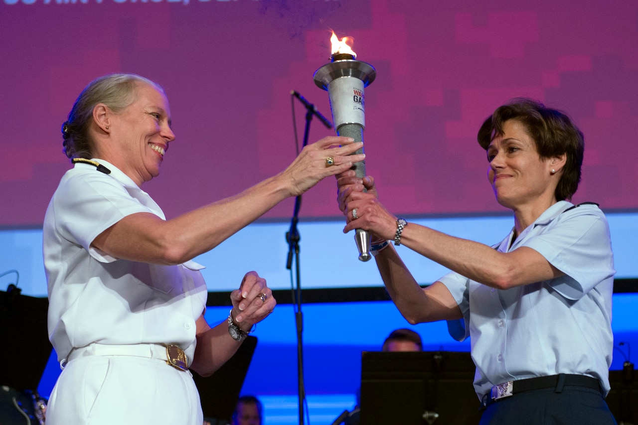 Navy Vice Admiral Mary Jackson, left, passes the Department of Defense Warrior Games torch to Air Force Lt. Gen. Gina Grosso during closing ceremonies for the 2017 Department of Defense Warrior Games in Chicago, July 8, 2017. DoD photo by EJ Hersom