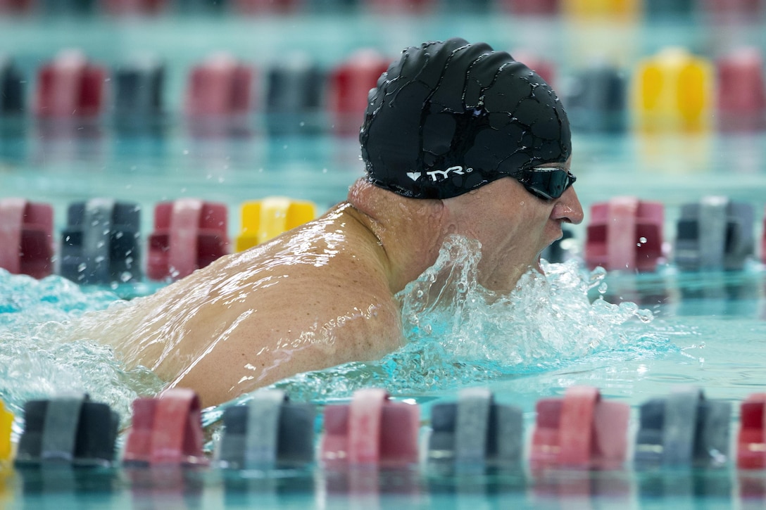 A swimmer breaks the surface during a breaststroke race.