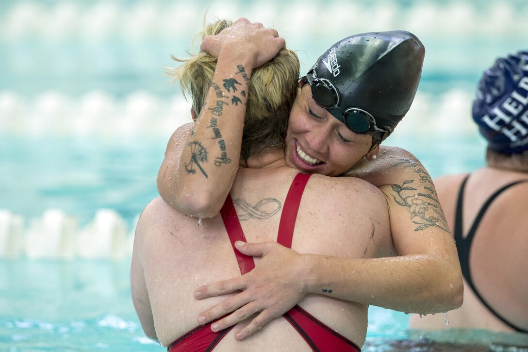 Two swimming competitors hug after completing a race.