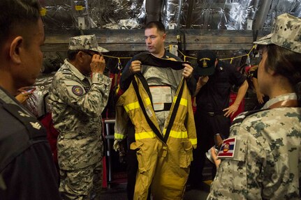 170530-N-PD309-114 SATTAHIP NAVAL BASE, Thailand (May 31, 2017) Sailors aboard littoral combat ship USS Coronado (LCS 4) discuss wearing a Firefighting Ensemble (FFE) to Royal Thai Navy sailors during a damage control training session in support of Cooperation Afloat Readiness and Training (CARAT) Thailand. CARAT is a series of Pacific Command-sponsored, U.S Pacific Fleet-led bilateral exercises held annually in South and Southeast Asia to strengthen relationships and enhance force readiness. CARAT exercise events cover a broad range of naval skill areas and disciplines including surface, undersea, air, and amphibious warfare; maritime security operations; riverine, jungle, and explosive ordnance disposal operations; combat construction; diving and salvage; search and rescue; maritime patrol and reconnaissance aviation; maritime domain awareness; military law, public affairs and military medicine; and humanitarian assistance and disaster response. (U.S. Navy photo by Mass Communication Specialist 3rd Class Deven Leigh Ellis/Released)