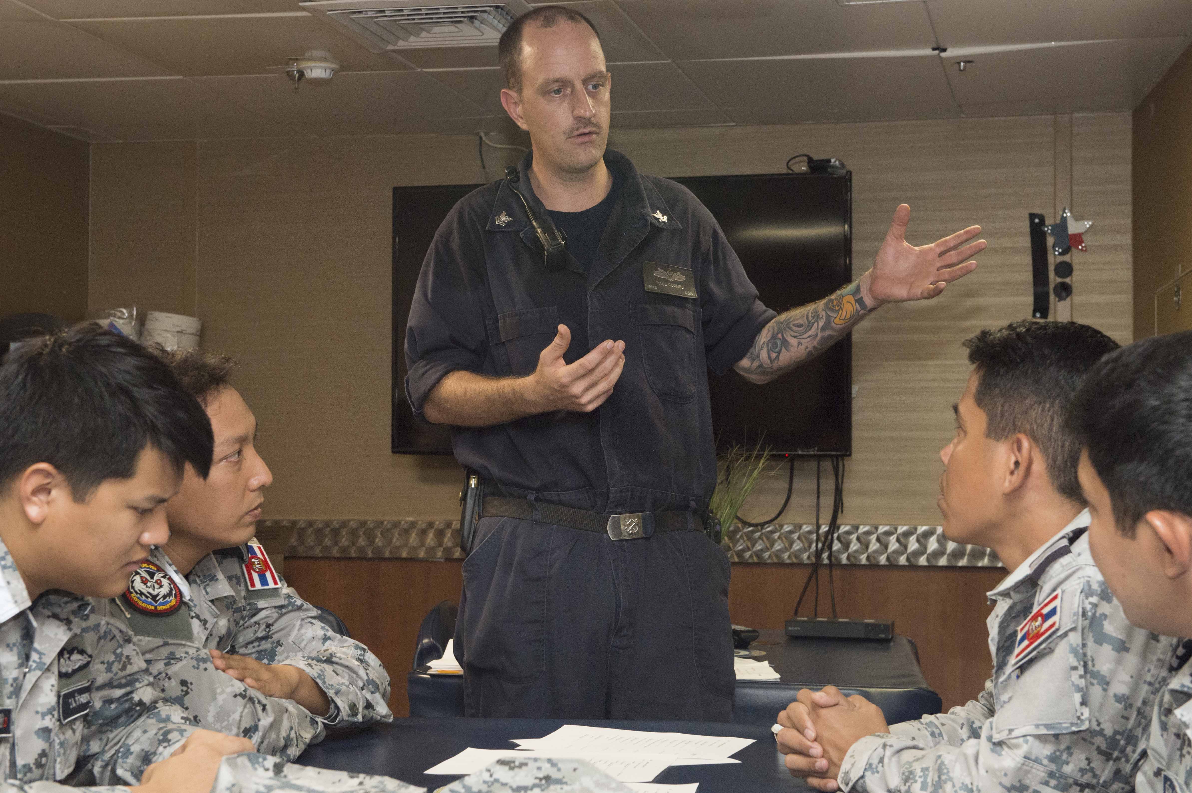 170530-N-PD309-121 SATTAHIP NAVAL BASE, Thailand (May 31, 2017) Boatswain's Mate 2nd Class Paul Coombs instructs Sailors from the Royal Thai Navy on personnel qualification standards aboard littoral combat ship USS Coronado (LCS 4) during Cooperation Afloat Readiness and Training (CARAT) Thailand. CARAT is a series of Pacific Command-sponsored, U.S Pacific Fleet-led bilateral exercises held annually in South and Southeast Asia to strengthen relationships and enhance force readiness. CARAT exercise events cover a broad range of naval skill areas and disciplines including surface, undersea, air, and amphibious warfare; maritime security operations; riverine, jungle, and explosive ordnance disposal operations; combat construction; diving and salvage; search and rescue; maritime patrol and reconnaissance aviation; maritime domain awareness; military law, public affairs and military medicine; and humanitarian assistance and disaster response. (U.S. Navy photo by Mass Communication Specialist 3rd Class Deven Leigh Ellis/Released)