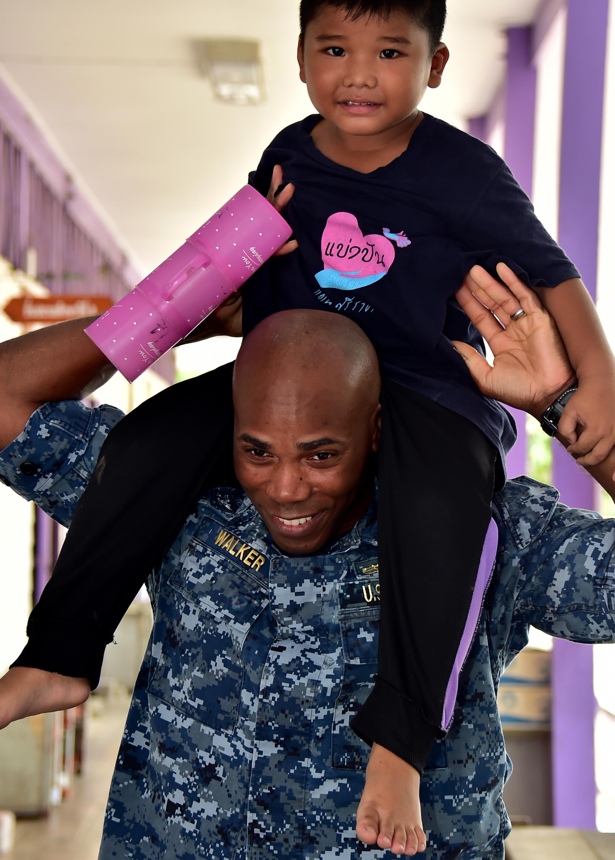 170531-N-QV906-017 PATTAYA, Thailand (May 31, 2017) Capt. Alexis Walker, Deputy Commander, Destroyer Squadron 7, raises a school child onto his shoulders from Banntunggard School during a community outreach event as part of Cooperation Afloat Readiness and Training Thailand 2017 May 31.  Cooperation Afloat Readiness and Training (CARAT) is a series of PACOM sponsored, U.S. Pacific Fleet led bilateral exercises held annually in South and Southeast Asia to strengthen relationships and enhance force readiness. CARAT exercise events cover a broad range of naval skill areas and disciplines including surface, undersea, air and amphibious warfare; maritime security operations; riverine, jungle and explosive ordnance disposal operations; combat construction; diving and salvage; search and rescue; maritime patrol and reconnaissance aviation; maritime domain awareness; military law, public affairs and military medicine; and humanitarian assistance, disaster response. (U.S. Navy photo by Mass Communication Specialist 1st Class Micah Blechner/RELEASED)