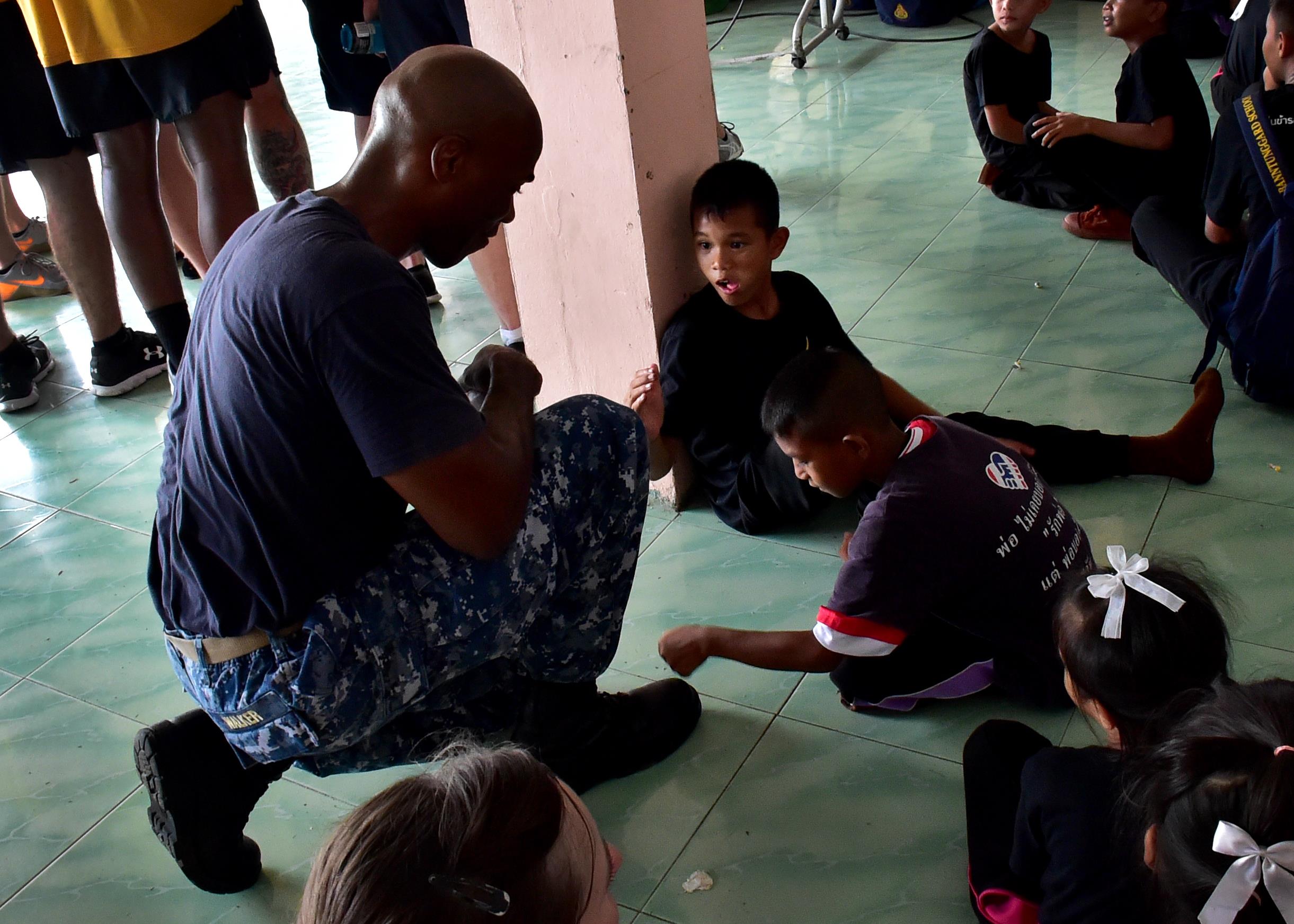 170531-N-QV906-519 PATTAYA, Thailand (May 31, 2017) Capt. Alexis Walker, Deputy Commander, Destroyer Squadron 7, lets a child from Banntunggard School test the strength of his steel-toed combat boots during a community outreach event as part of Cooperation Afloat Readiness and Training Thailand 2017 May 31.  Cooperation Afloat Readiness and Training (CARAT) is a series of PACOM sponsored, U.S. Pacific Fleet led bilateral exercises held annually in South and Southeast Asia to strengthen relationships and enhance force readiness. CARAT exercise events cover a broad range of naval skill areas and disciplines including surface, undersea, air and amphibious warfare; maritime security operations; riverine, jungle and explosive ordnance disposal operations; combat construction; diving and salvage; search and rescue; maritime patrol and reconnaissance aviation; maritime domain awareness; military law, public affairs and military medicine; and humanitarian assistance, disaster response. (U.S. Navy photo by Mass Communication Specialist 1st Class Micah Blechner/RELEASED)