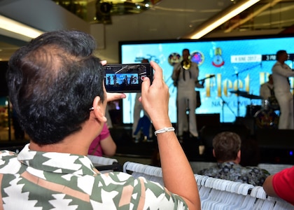 170604-N-QV906-080 PATTAYA, Thailand (June 4, 2017) A member of the crowd records the U.S. 7th Fleet Band, Orient Express, jam out during a performance at Golden Plaza Mall in Pattaya, Thailand, while participating in Cooperation Afloat Readiness and Training Thailand 2017 June 3.  Cooperation Afloat Readiness and Training (CARAT) is a series of PACOM sponsored, U.S. Pacific Fleet led bilateral exercises held annually in South and Southeast Asia to strengthen relationships and enhance force readiness. CARAT exercise events cover a broad range of naval skill areas and disciplines including surface, undersea, air and amphibious warfare; maritime security operations; riverine, jungle and explosive ordnance disposal operations; combat construction; diving and salvage; search and rescue; maritime patrol and reconnaissance aviation; maritime domain awareness; military law, public affairs and military medicine; and humanitarian assistance, disaster response. (U.S. Navy photo by Mass Communication Specialist 1st Class Micah Blechner/RELEASED)