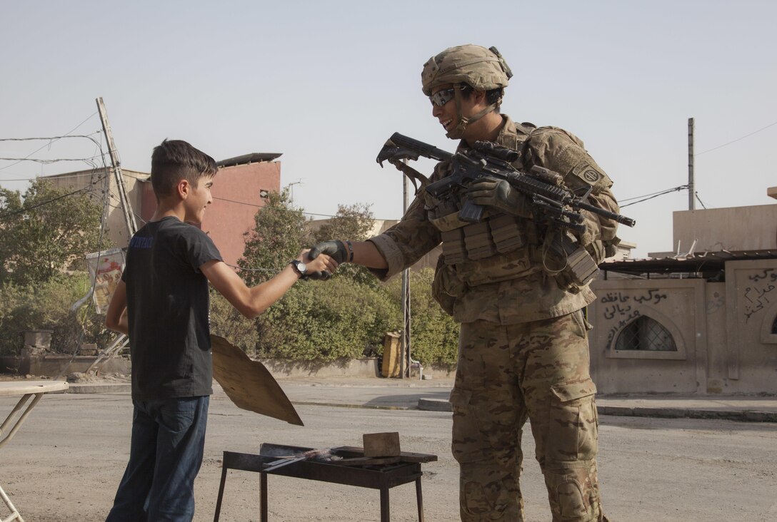 A U.S. paratrooper shakes the hand of a young boy while on patrol in 
Mosul, Iraq, July 4, 2017. Army photo by Cpl. Rachel Diehm