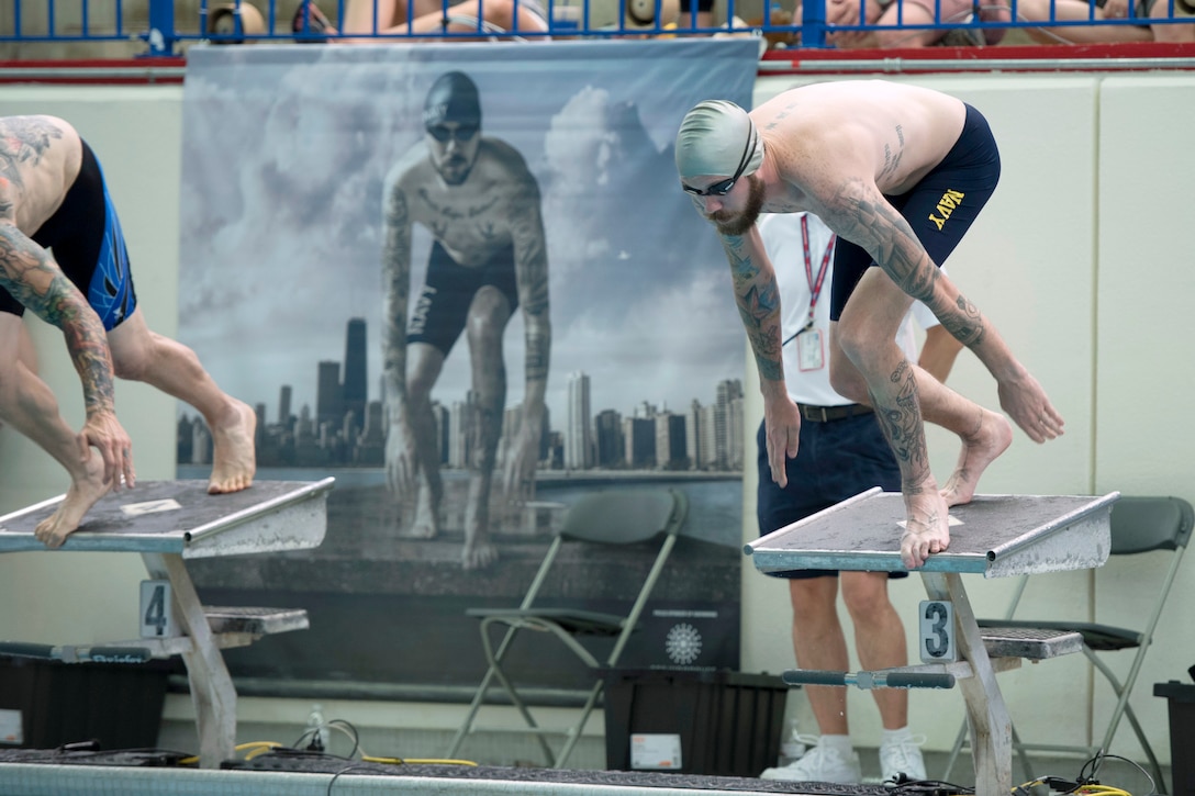 Navy veteran Petty Officer 1st Class Ryan Shannon takes his position on the starting blocks near a poster featuring him in the same position during the swimming competition at the 2017 Department of Defense Warrior Games in Chicago, July 8, 2017. DoD photo by Roger L. Wollenberg