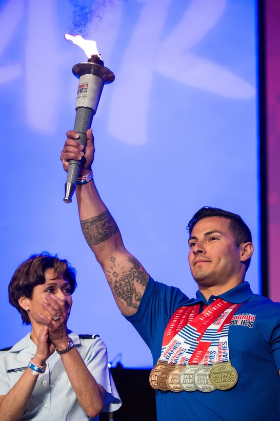 The Team Air Force Heart of the Team winner recieves the torch from Team Navy during the 2017 Department of Defense Warrior Games closing ceremony in Chicago, July 8, 2017. The Air Force will host the 2018 Warrior Games. The Heart of the Team award is given to one member on each team who best exemplifies the camaraderie of the sport. DoD photo by Army Sgt. James K. McCann
