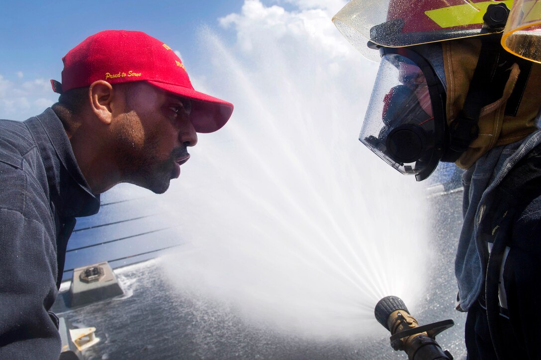 Navy Petty Officer 2nd Class Dominique Cisneros gives firefighting hose handling tips to a sailor during a general quarters training evolution aboard the Arleigh Burke-class guided-missile destroyer USS Pinckney in the Pacific Ocean, July 2, 2017. Cisneros is a Damage Controlman. Navy photo by Petty Officer 2nd Class Craig Z. Rodarte