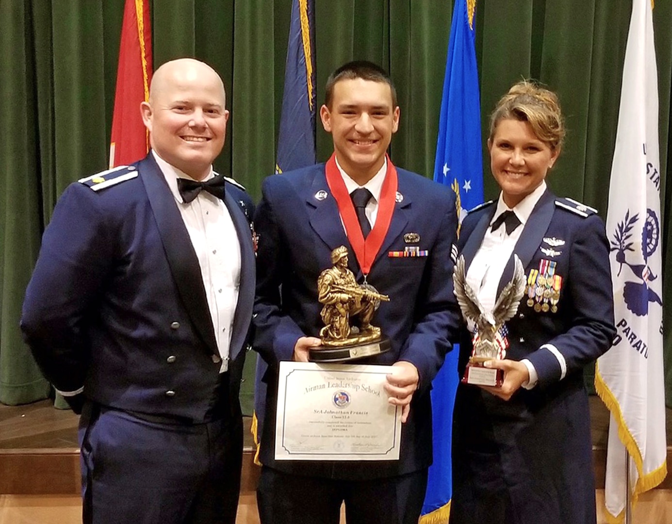 Senior Airman Jonathan Francis, 433rd Operations Support Squadron intelligence flight, Maj. Wesley Lowery, 433rd OSS chief, and Lt. Col. Kari Hill, 433rd OSS commander, display Francis' Airman Leadership School awards July 5,2017 at Joint Base San Antonio-Lackland, Texas. Francis  was awarded the Distinguished Graduate and the Commandant's Award. (Courtesy photo by Ester Francis)