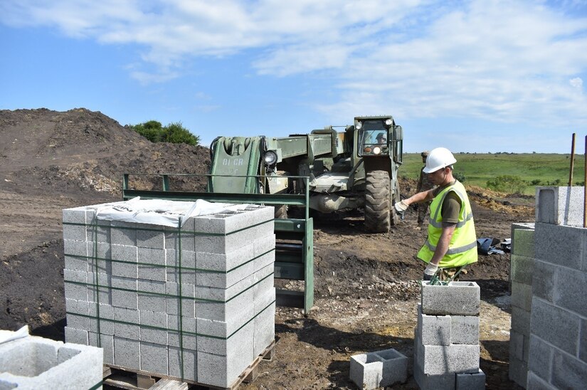 A Soldier of the 225th Field Engineers, U.K. Royal Monmouthshire Royal Engineers (Militia), ground guides Staff Sgt. Benjamin Sykora of the 926th Engineer Brigade, United States Army Reservse, as he moves construction materials. The concrete blocks are for a Light Demolition Range. The construction project is a part of Operation Resolute Castle 2017 at the Joint National Training Center, Cincu, Romania. Resolute Castle is an exercise strengthening the NATO alliance and enhancing its capacity for joint training and response to threats within the region.