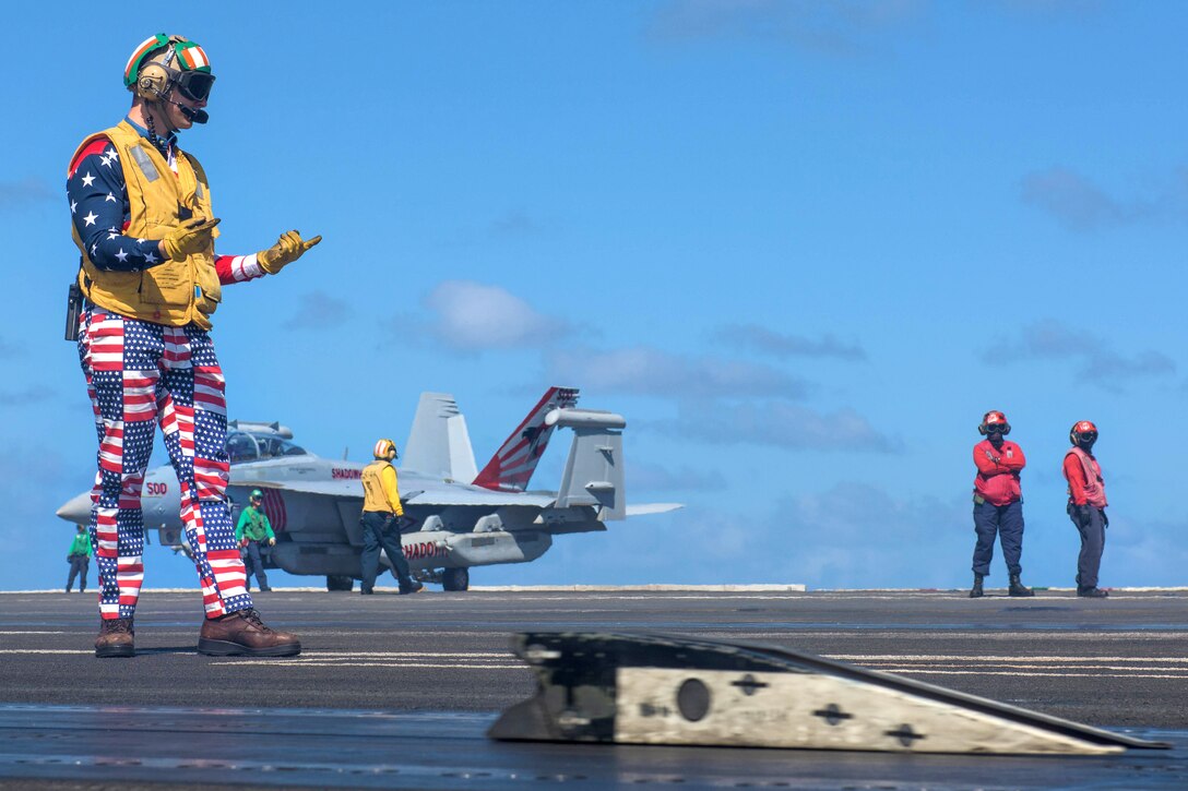Navy Lt. Chris Williams signals for the movement of the catapult shuttles on the flight deck aboard the aircraft carrier USS Ronald Reagan in the Pacific Ocean, July 4, 2017. Navy photo by Petty Officer 2nd Class Kenneth Abbate