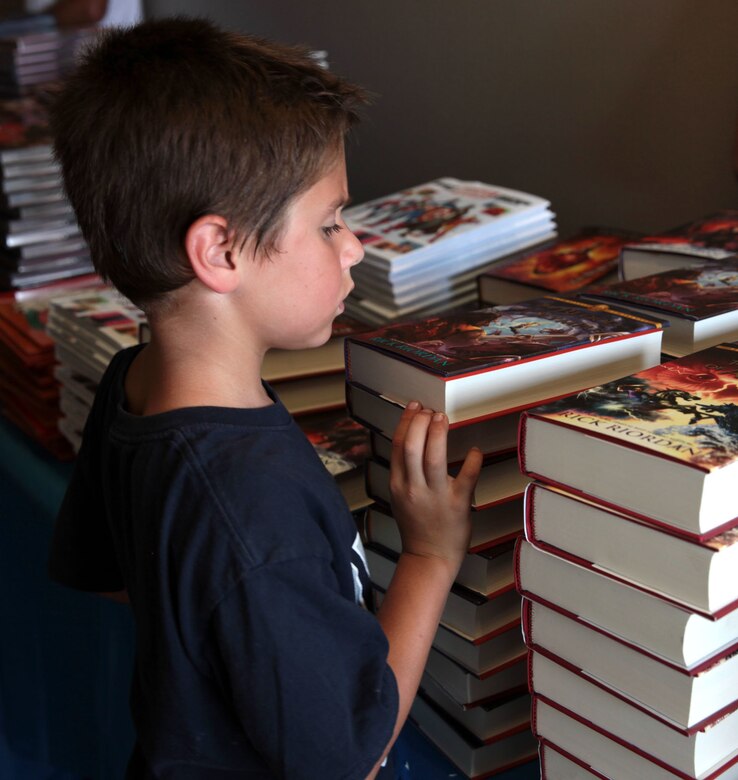 A young child looks over donated books to decide which to keep during Books on Bases, Camp Pendleton, Calif., July 8th, 2017. Books on Bases brings books to military children and is a part of Blue Star Families' and The Walt Disney Company's  ongoing effort to to support military families across the nation. (U.S. Marine Corps Photo by LCpl. Dylan Chagnon)