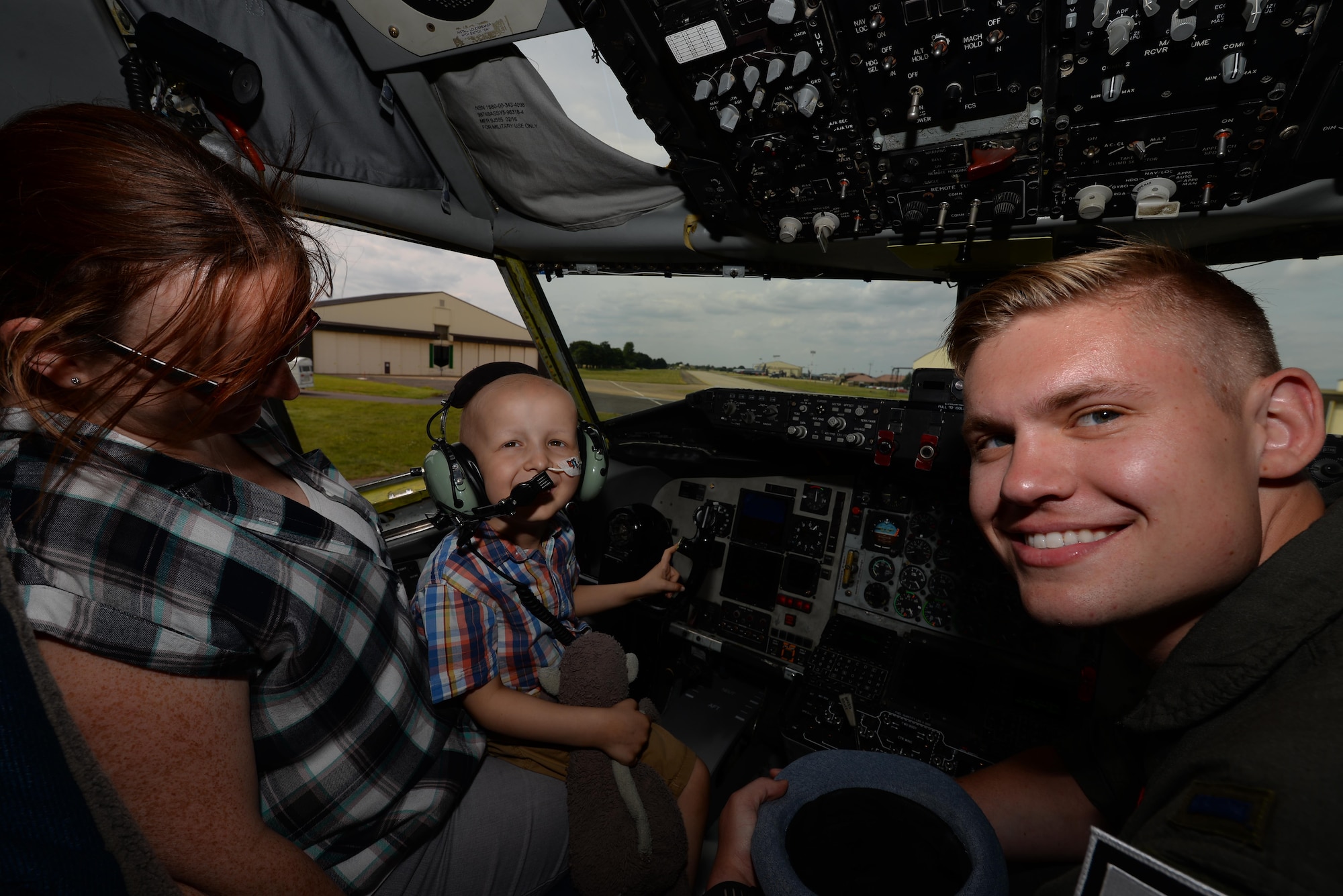 U.S. Air Force 1st Lt. Brendan Keiper, right, 351st Air Refueling Squadron pilot, takes a photo with  Jay Davidson and his mother, Keily, on the flight deck of a KC-135 Stratotanker during a Pilot for a Day visit July 7, 2017, on RAF Mildenhall, England. Jay toured three different aircraft and visited the air traffic control tower during his visit. Jay was diagnosed with high-risk medulloblastoma in January 2017. (U.S. Air Force photo by Staff Sgt. Micaiah Anthony)