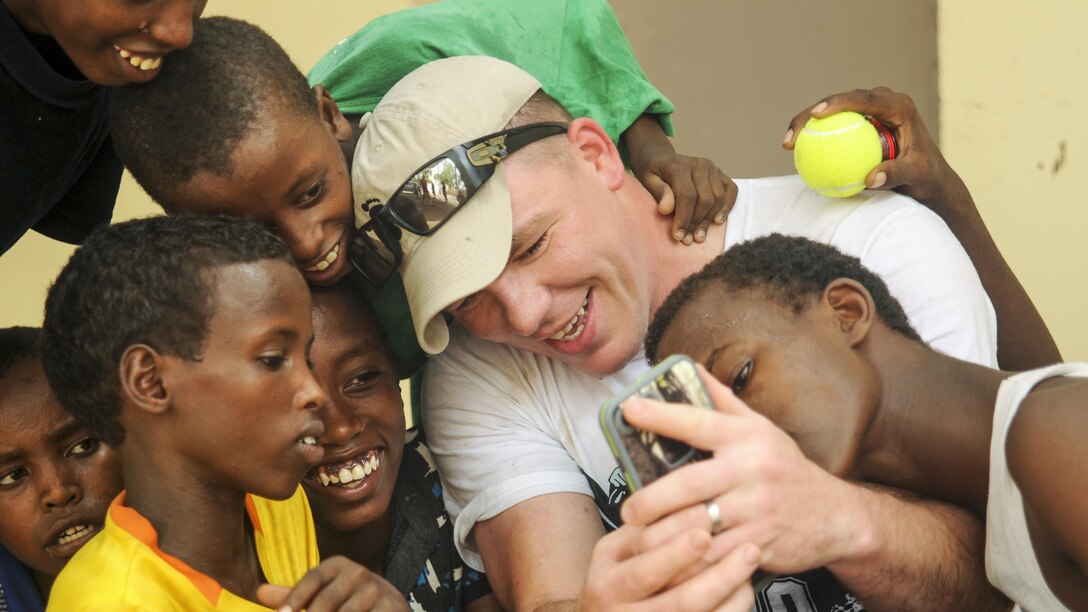 Army Spc. Rodney Drew takes a picture with children at Caritas, a facility that provides meals and medical care to youth in Djibouti, July 06, 2017. Drew is assigned to Company B, 1st Battalion, 153rd Infantry Regiment. Army National Guard photo by Spc. Victoria Eckert