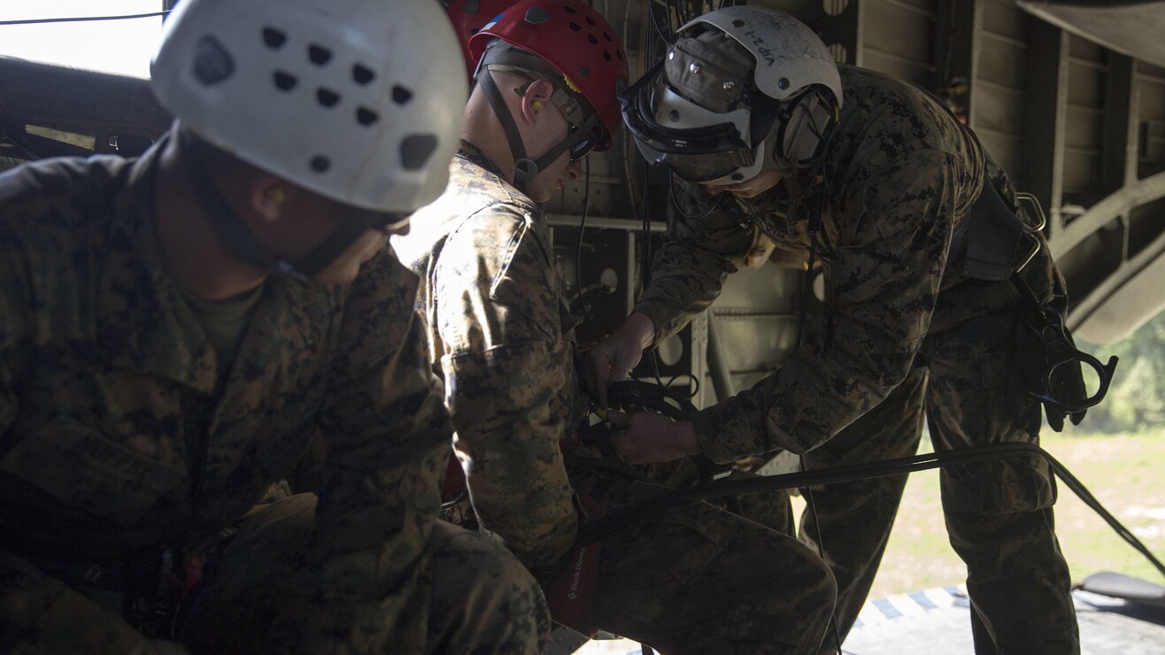 Staff Sgt. Jerry Colvin connects an instructor to a rappel line during a ceremony at Stone Bay, a Camp Lejeune satellite training area, N.C., May 17, 2017.  The ceremony marks the reopening of Landing Zone Vulture, which closed Sept. 2, 2015 after a CH-53 crashed resulting in the death of one Marine.  The instructors took the opportunity to memorialize their fallen Marine, Staff Sgt. Jonathan Lewis, through the sustainment rappel. Colvin is with EOTG, II Marine Expeditionary Force Headquarters Group.