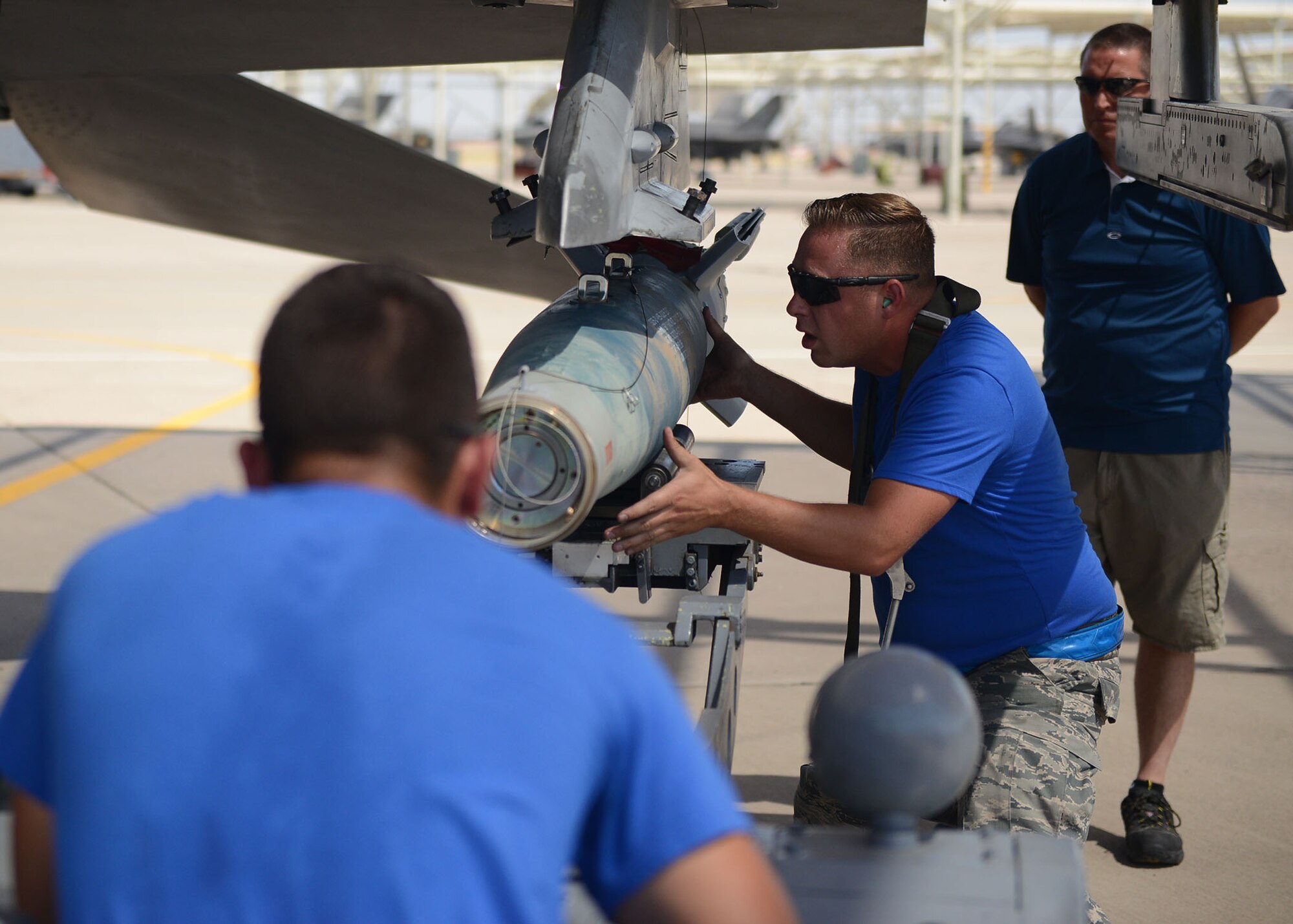 Staff Sgt. Jonathan Picher, 309th Aircraft Maintenance Unit load crew chief, ensures the GBU-12 Paveway II connections line up properly while Airman 1st Class Antonio Rosario, 309th AMU load crew member, guides it in with an aerial stores lift truck during the quarterly load crew competition at Luke Air Force Base, Ariz., July 7, 2017. The goal of the competition was to load two GBU-12s in under 30 minutes. (U.S. Air Force photo by Senior Airman James Hensley)