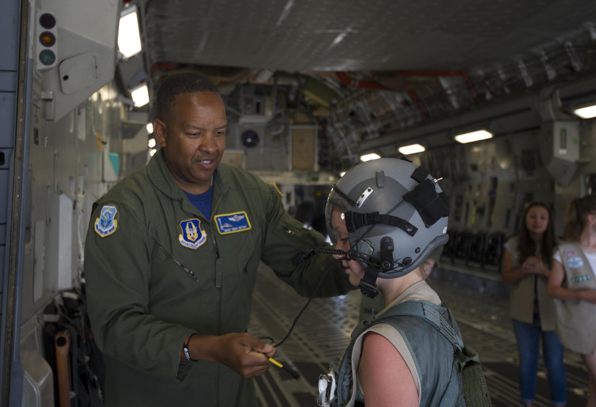 Senior Master Sgt. Derek Bryant, a loadmaster with the 446th Operations Group, helps a Girl Scout don a helmet and safety harness, during a base tour July 9, 2017, at McChord Field. SMSgt Bryant discussed what it’s like to be a loadmaster and showed various tasks aircrews perform. During the visit, seven girl scouts were able to tour the 446th AW, a C-17 Globemaster III, control tower, and learned survival tips from a Survival, Evasion, Resistance and Escape, instructor. (U.S. Air Force photo by Tech. Sgt. Bryan Hull)