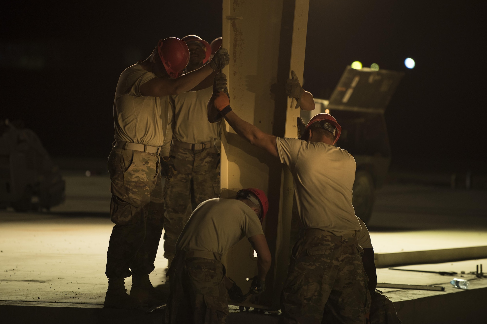 Airmen assigned to the 557th Expeditionary RED HORSE hold a vertical column in place as it is being secured June 27, 2017, in Southwest Asia. The squadron is tasked with constructing a new 332nd Air Expeditionary Wing mission support industrial complex and life support area, to include facilities, utilities and roads, providing the wing with increased capabilities. (U.S. Air Force photo/Senior Airman Damon Kasberg)