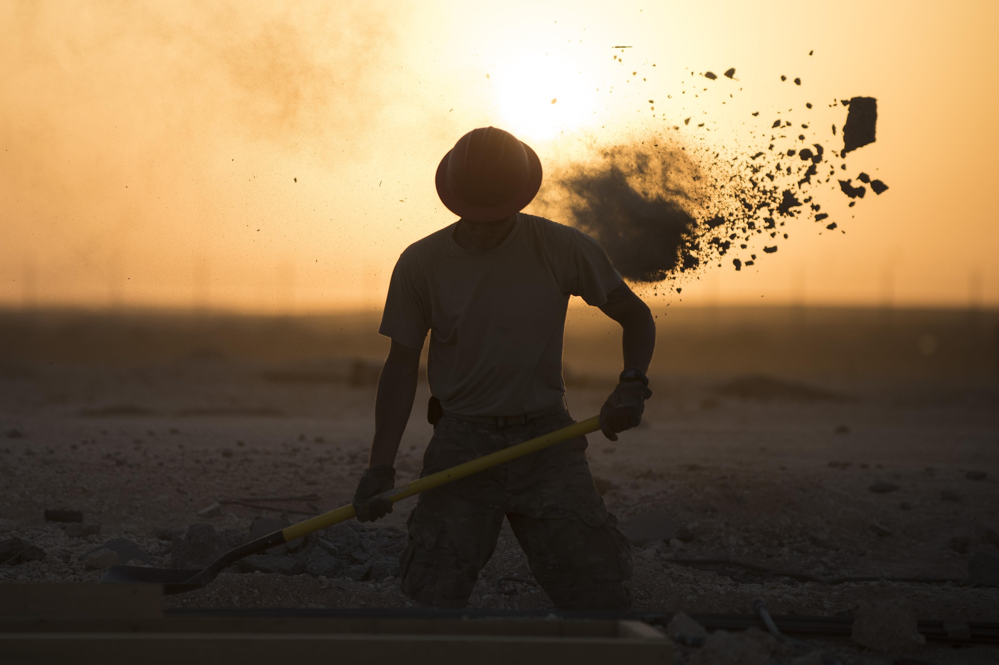 Staff Sgt Dominic Koah, 557th Expeditionary RED HORSE water fuels system maintenance craftsman, shovels dirt and concrete away from a construction site June 27, 2017, in Southwest Asia. Working through extreme heat and high winds members of RED HORSE construct pre-engineered buildings vital to the expansion of the 332nd Air Expeditionary Wing and its operational capabilities. (U.S. Air Force photo/Senior Airman Damon Kasberg)