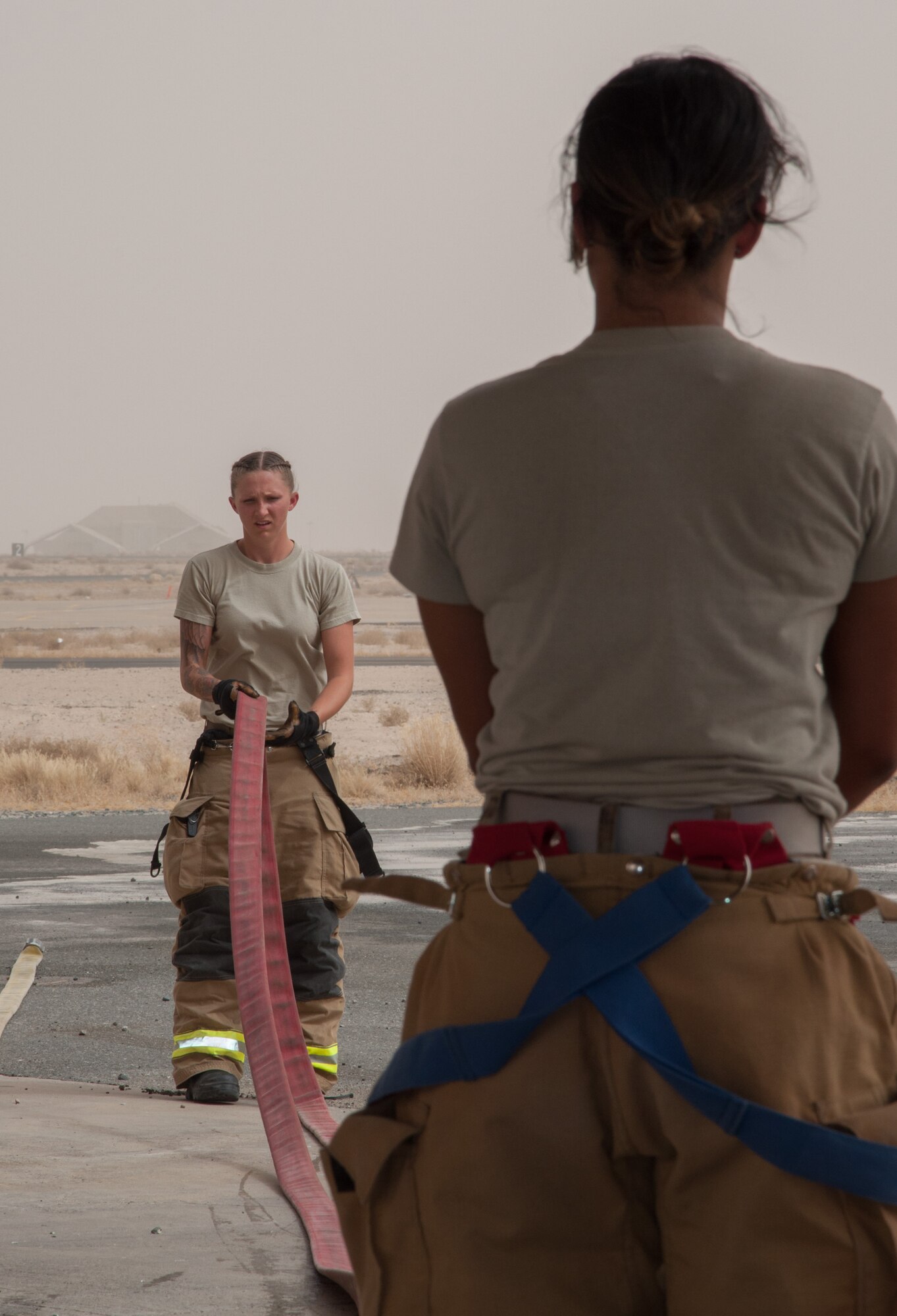 Senior Airman Ashley Eisenbarth (left) stretches out a hose line, with assistance from Staff Sgt. Jessica Mendoza Sunday, June 25, 2017 at a 386th Air Expeditionary Wing fire station at an undisclosed location in Southwest Asia. (U.S. Air Force photo by Master Sgt. Eric M. Sharman)