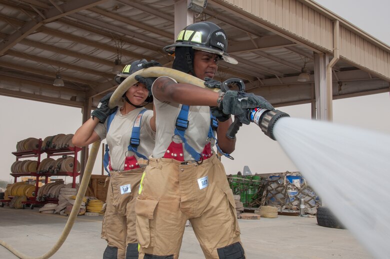 Senior Airman Christa Dennis (right) operates a hand line with assistance from Senior Airman Ayanna Gaskin Sunday, June 25, 2017 at a 386th Air Expeditionary Wing fire station at an undisclosed location in Southwest Asia. Dennis and Gaskin are firefighters assigned to the 386th Expeditionary Civil Engineer Squadron. (U.S. Air Force photo by Master Sgt. Eric M. Sharman)