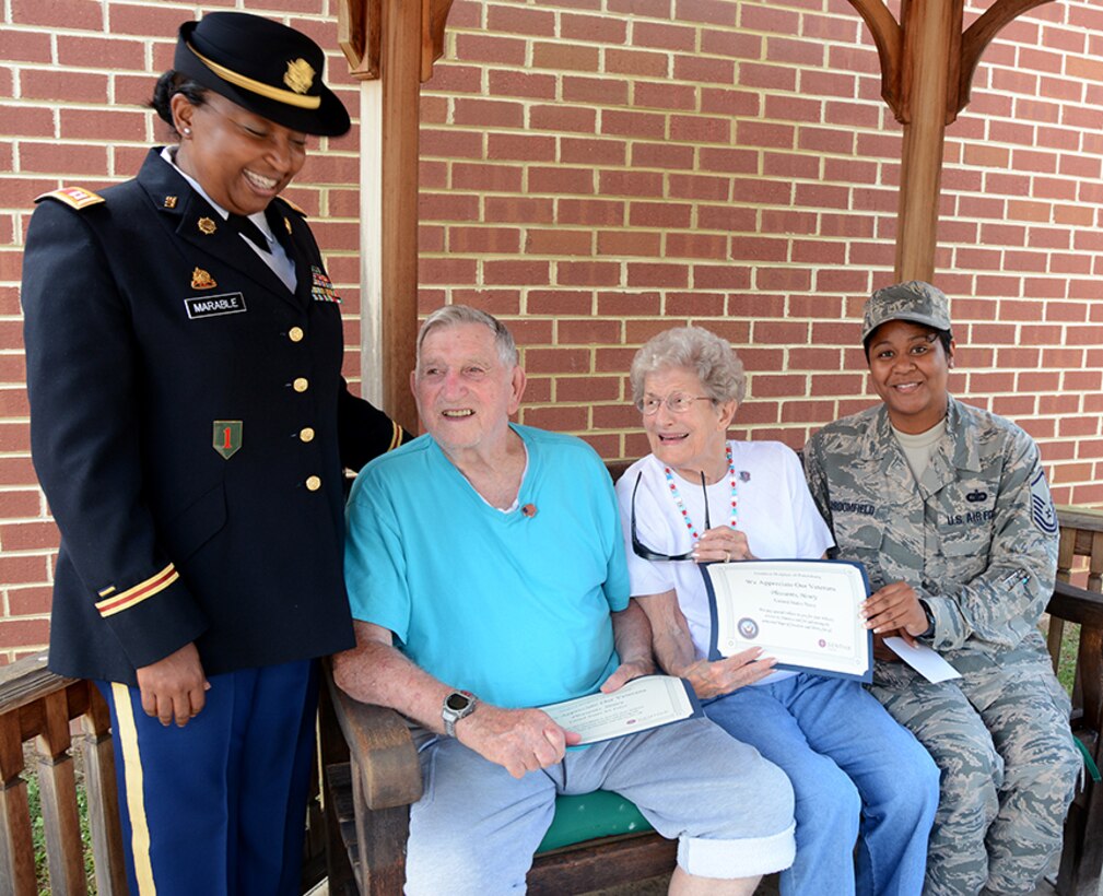 Air Force Master Sgt. Nikki Broomfield, right, military human resources specialist, Resource Management Division, Command Support Directorate, Defense Logistics Agency Aviation, and Army Capt. Constance Marable, left, Advance Individual Training Tango Company commander, 266th Quartermaster Battalion, Fort Lee, Virginia,  present a certificate of appreciation to Henry Pleasants, a World War II veteran who suffers from Alzheimer’s, with his wife, Laura Pleasants, after an Independence Day ceremony to honor veterans at the Dunlop House, an assisted living facility, in Colonial Heights, Virginia, July 6, 2017.