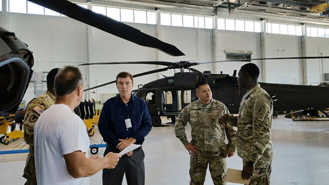 Defense Logistics Agency Aviation, Readiness Cell team members from the Army Customer Facing Division discuss Army aviation readiness with members of the 1108th Theater Aviation Sustainment Maintenance Group Mississippi Army National Guard, Gulfport, Mississippi, during their outreach site visit June 26-27, 2017.  Pictured left to right: Ronald Balius, sheet metal mechanic, and Army Maj. Wangson Sylvien. logistics maintenance officer from the 1108th, Bob Johnson, UH-60 weapons system program manager and Army Maj. Alex Shimabukuro, operations officer from DLA Aviation; and Army Capt. Jeremy Forrest, a logistics officer with the 1108th. 