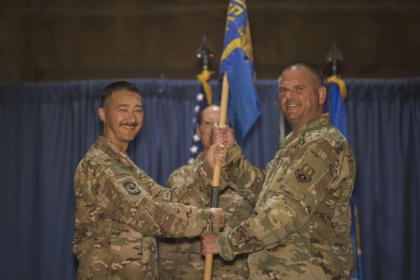 Col. Christopher K. Fuller, 332nd Expeditionary Mission Support Group commander, left, passes the guidon to Maj. Matthew W. Tronnes, during the 332nd Expeditionary Civil Engineer Squadron change of command ceremony July 10, 2017, in Southwest Asia. The passing of a guidon symbolizes a unit’s transfer of command. (U.S. Air Force photo/Senior Airman Damon Kasberg)