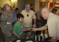 Mr. Paul Burke, Joint Non-Lethal Weapons Directorate Combatant Command Liaison Officer to U.S. Special Operations Command, demonstrates the payload of a 40mm sponge grenade round to one of the participants at the U.S. Central Command Family Day on June 16.