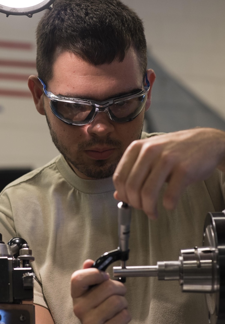 Airman 1st Class Christopher Brown, 27th Maintenance Squadron Aircraft Metals Technology apprentice, measures the width of a piece of metal in a precision lathe at Cannon Air Force Base, New Mexico, June 21, 2017. Brown has been training for the last eight months and will be finished in November. Each Airman has to be trained on every piece of equipment in the shop. (U.S. Air Force photo by Staff Sgt. Michael Washburn/Released)