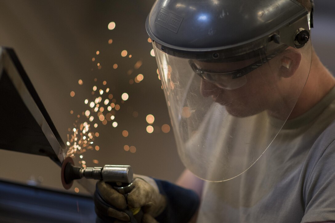 Airman 1st Class Patrick Ragan, 27th Maintenance Squadron Aircraft Metals Technology apprentice, grinds down the side of low-pac cover at Cannon Air Force Base, New Mexico, June 21, 2017. The metals tech shop can fabricate or fix parts for any aircraft here at Cannon. (U.S. Air Force photo by Staff Sgt. Michael Washburn/Released)