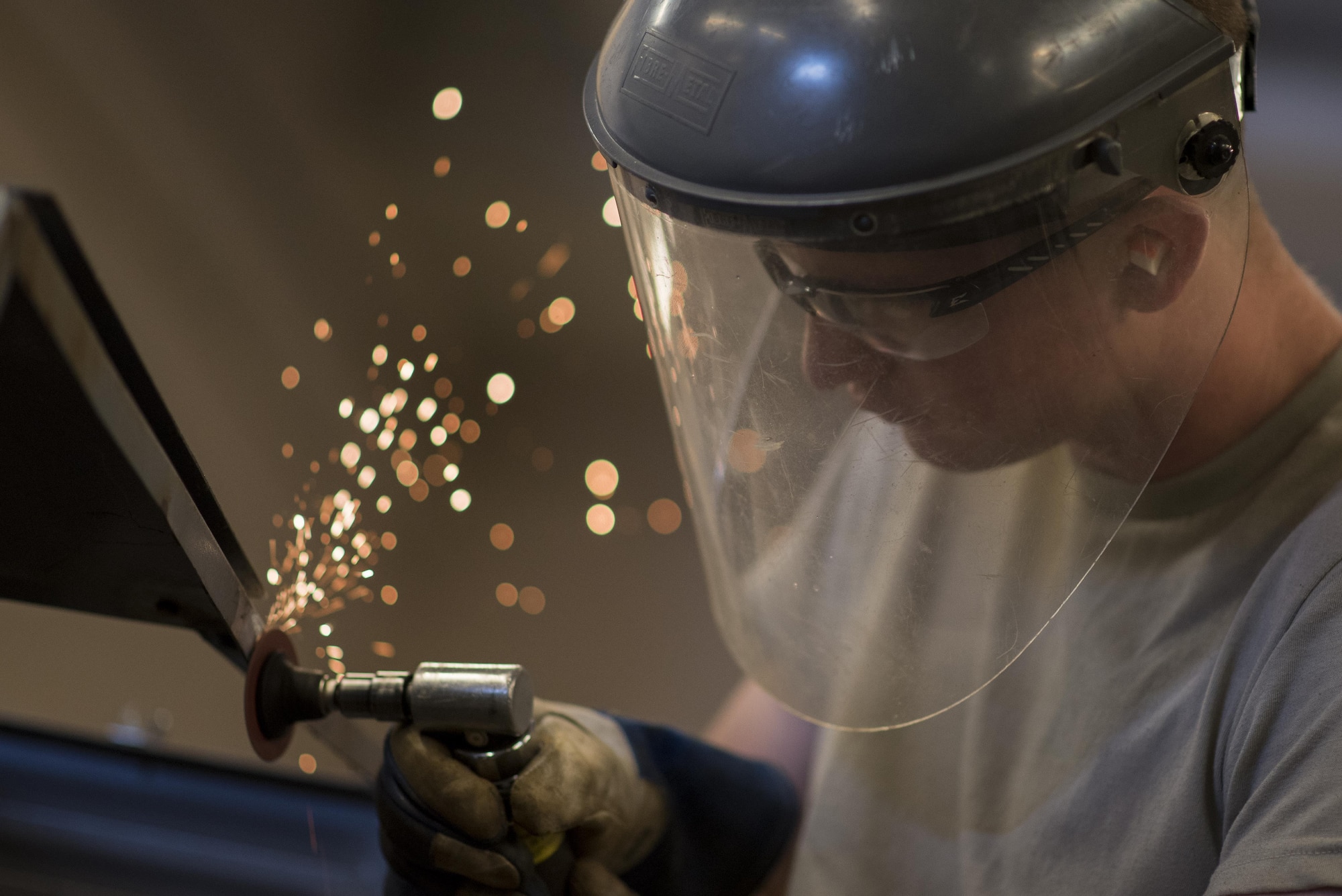 Airman 1st Class Patrick Ragan, 27th Maintenance Squadron Aircraft Metals Technology apprentice, grinds down the side of low-pac cover at Cannon Air Force Base, New Mexico, June 21, 2017. The metals tech shop can fabricate or fix parts for any aircraft here at Cannon. (U.S. Air Force photo by Staff Sgt. Michael Washburn/Released)