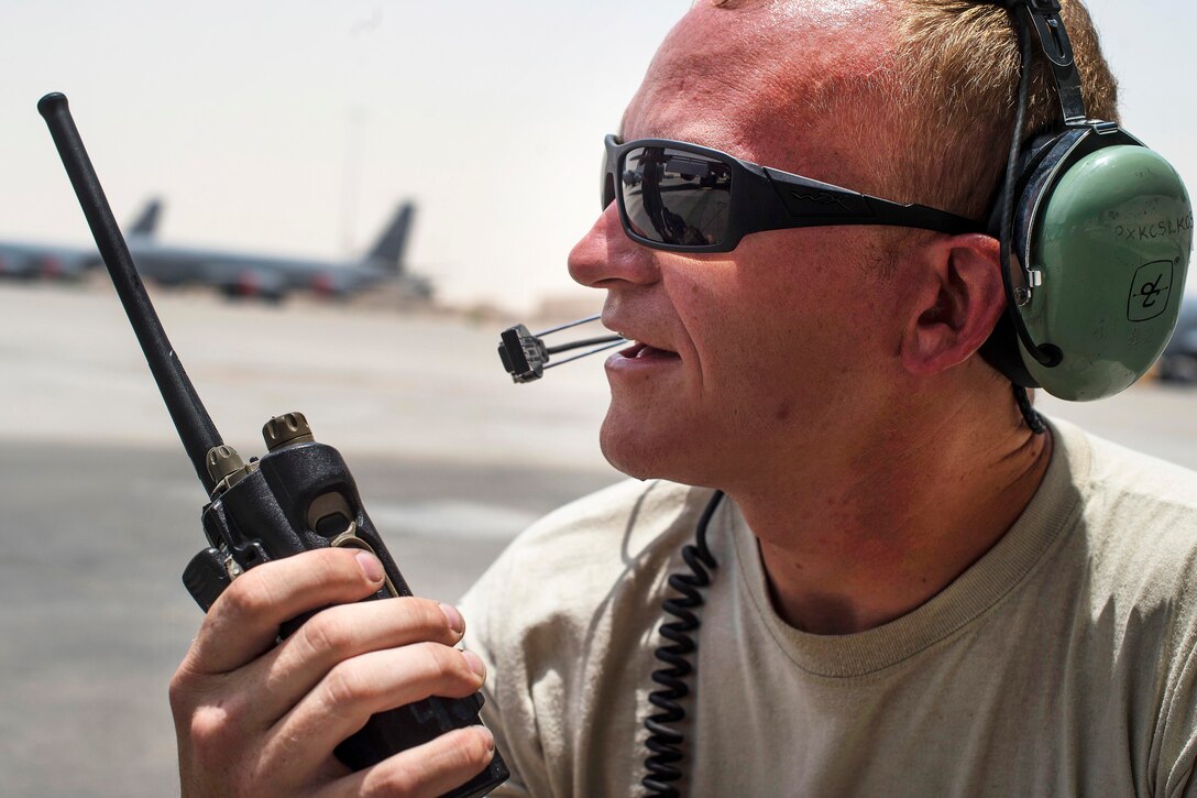 An airman uses a radio to communicate with pilots on the flightline at Al Udeid Air Base, Qatar, July 6, 2017. The airman is a maintainer assigned to the 379th Expeditionary Aircraft Maintenance Squadron. Air Force photo by Staff Sgt. Trevor T. McBride
