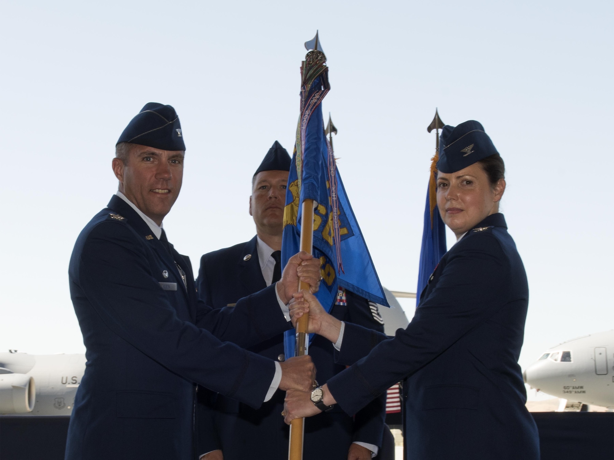 U.S. Air Force Col. John Klein, 60th Air Mobility Wing commander, hands the guidon to Col. Theresa E. Weems, 60th Operations Group commander, as she assumes command during the 60th OG Change of Command ceremony at Travis Air Force Base, Calif., Jul 7, 2017. The 60th OG is responsible for daily air operations of the largest air mobility wing in the U.S. Air Force. (U.S. Air Force photo by Heide Couch)