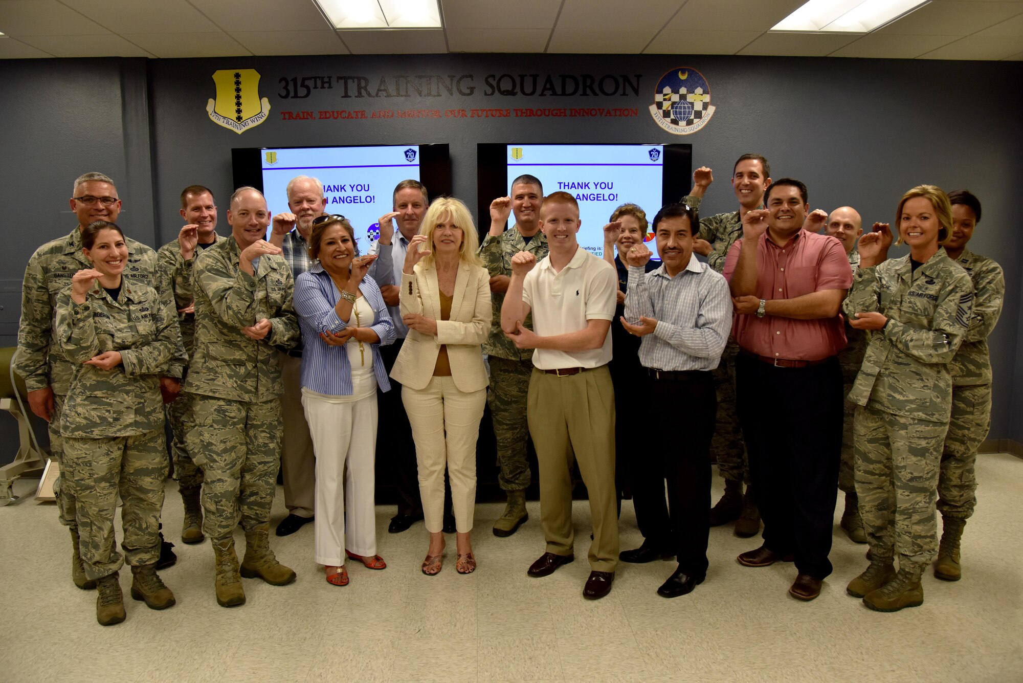Goodfellow Air Force Base and San Angelo, Texas leaders pose for a photo while doing the 315th Training Squadron hand sign at the Di Tommaso Hall on Goodfellow Air Force Base, Texas, July 7, 2017. The group photo was the last event in a base orientation tour for new community leaders. (U.S. Air Force photo by Staff Sgt. Joshua Edwards/Released)