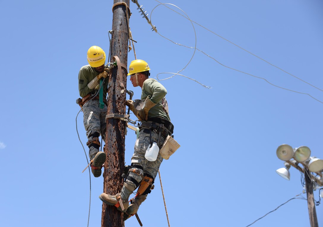 Airman 1st Class Channon Abercrombie and Airman Dylan Anderson, 366th Training Squadron electrical systems course students, prepare to install a support arm for a guy wire. The guy wire keeps outward tension on the pole, in order to keep the electrical wire from pulling the pole inward. (U.S. Air Force photo by Senior Airman Robert L. McIlrath)