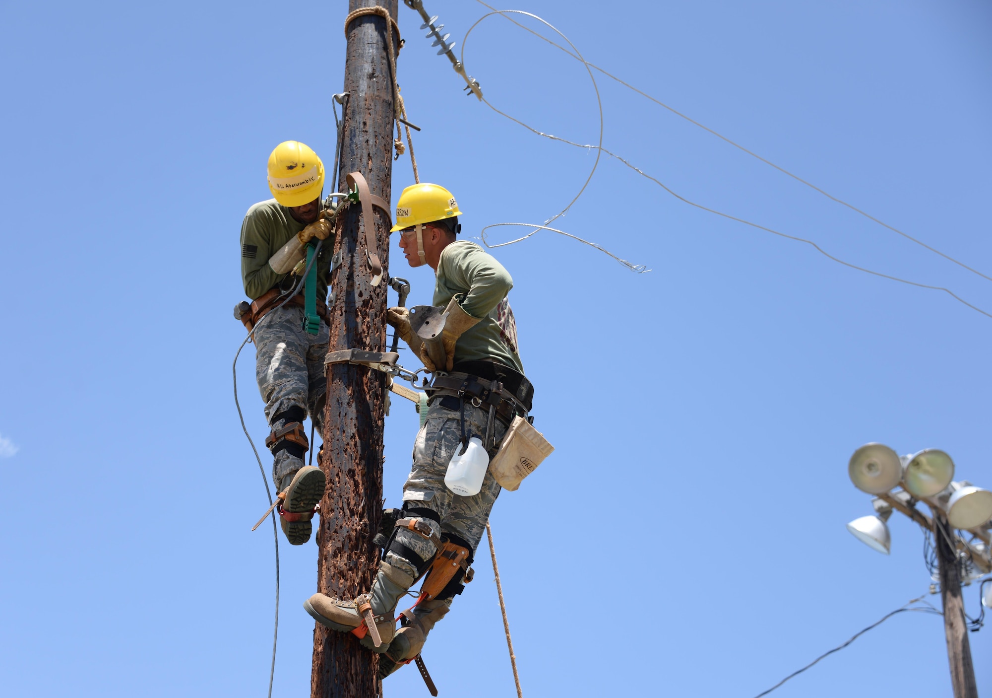 Airman 1st Class Channon Abercrombie and Airman Dylan Anderson, 366th Training Squadron electrical systems course students, prepare to install a support arm for a guy wire. The guy wire keeps outward tension on the pole, in order to keep the electrical wire from pulling the pole inward. (U.S. Air Force photo by Senior Airman Robert L. McIlrath)