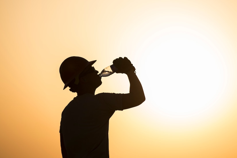 An Airman assigned to the 557th Expeditionary RED HORSE, drinks waster while working on a construction site June 27, 2017, in Southwest Asia. Working through extreme heat and high winds members of RED HORSE construct pre-engineered buildings vital to the expansion of the 332nd Air Expeditionary Wing and its operational capabilities. (U.S. Air Force photo/Senior Airman Damon Kasberg)