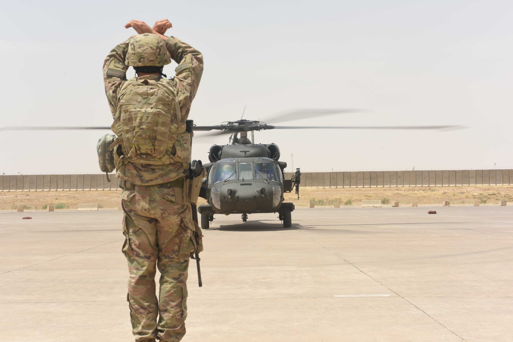 U.S. Air Force Tech. Sgt. Joseph Tenebruso, the expeditionary maintenance flight chief deployed in support of Combined Joint Task Force – Operation Inherent Resolve and assigned to the 370th Air Expeditionary Advisory Group, Detachment 1, marshals in an UH-60 Black Hawk helicopter at Qayyarah West Airfield, Iraq, July 2, 2017. The expeditionary maintenance liaisons marshal incoming aircraft at Qayyarah West to maintain an efficient parking plan at the logistical hub for the Mosul offensive. CJTF-OIR is the global Coalition to defeat ISIS in Iraq and Syria. (U.S. Air Force photo by Tech. Sgt. Jonathan Hehnly)