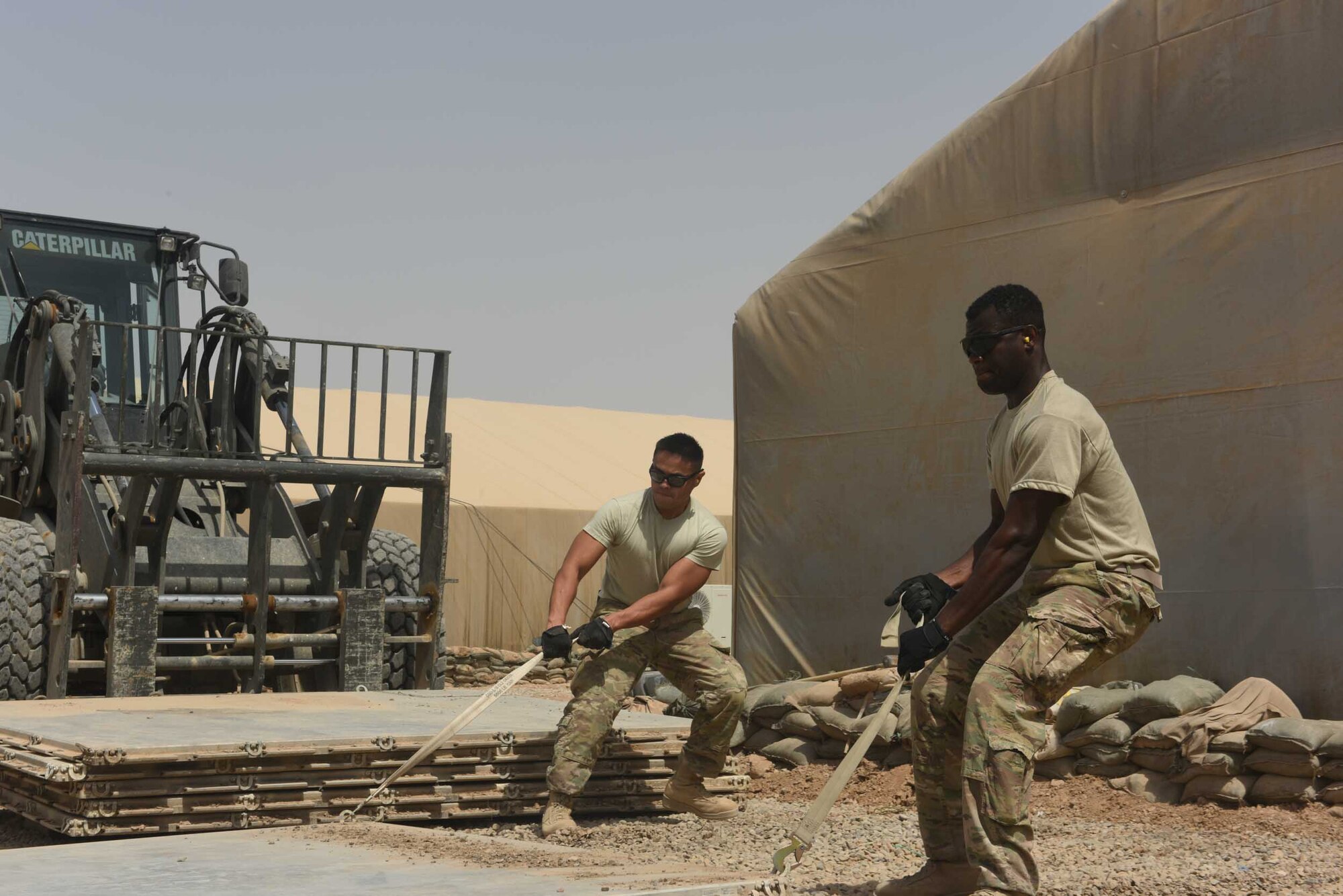 U.S. Air Force Senior Airman Tristan Gavia and Airman 1st Class Nestore Chenue, both air transportation specialists deployed in support of Combined Joint Task Force – Operation Inherent Resolve and assigned to the 442nd Air Expeditionary Squadron, work together to pull a 463L pallet during a pallet recovery mission at Qayyarah West Airfield, Iraq, July 2, 2017. The aerial porters recovered the unclaimed pallets as part of a larger U.S. Air Force aerial port pallet recovery initiative taking place across Iraq.  CJTF-OIR is the global Coalition to defeat ISIS in Iraq and Syria. (U.S. Air Force photo by Tech. Sgt. Jonathan Hehnly)