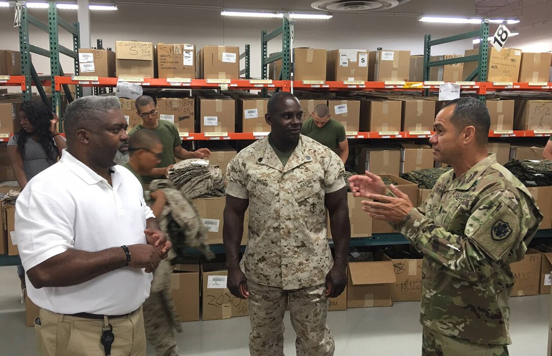 DLA Senior Enlisted Leader Command Sgt. Maj. Charles Tobin, right, discusses the logistics of uniform issue with Rick Green, DLA Troop Support, and Staff Sgt. Brown, Marine Corps Recruiting Station San Diego.