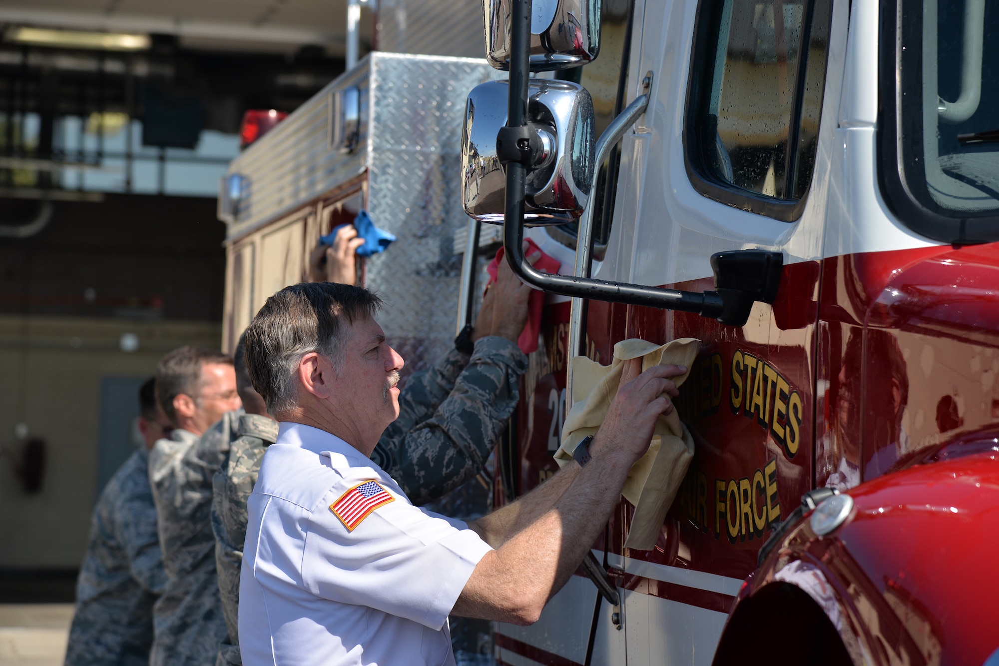 Firefighters and guests in attendance dry the new brush truck during the fire department’s truck christening ceremony July 6, 2017, at Malmstrom Air Force Base, Mont. The truck can carry 500 gallons of water, 20 gallons of Class A foam and is capable of pumping and rolling to allow it to extinguish grass and wildfires. (U.S. Air Force photo/Airman 1st Class Daniel Brosam)