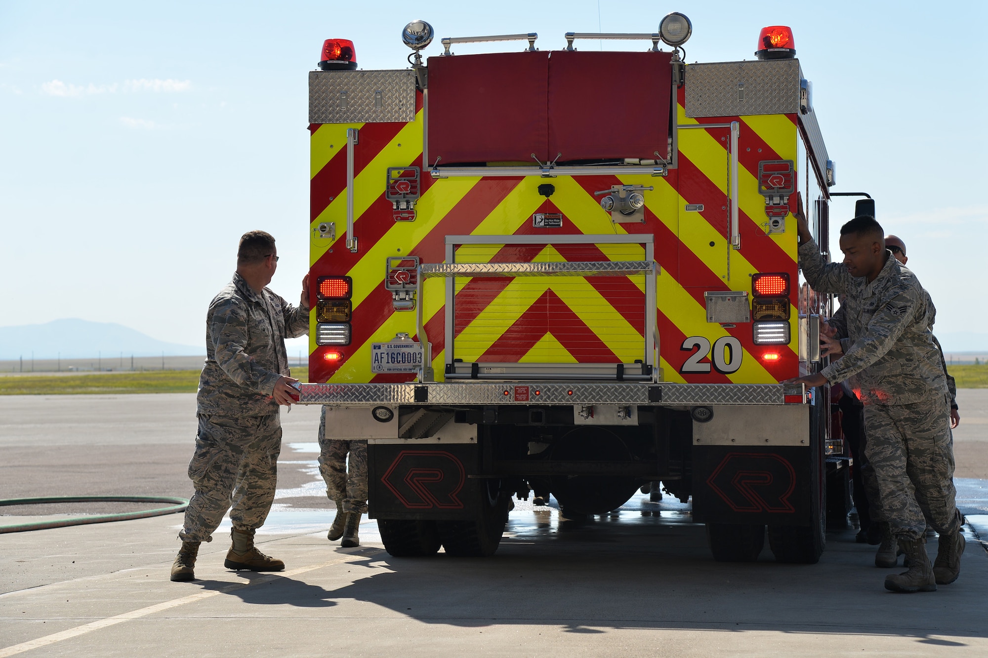 Firefighters and guests in attendance push the new brush truck into the vehicle storage bay during the fire department’s truck christening ceremony July 6, 2017, at Malmstrom Air Force Base, Mont. This part of the ceremony pays tribute to an old tradition dating back to the horse-drawn pumper days. (U.S. Air Force photo/Airman 1st Class Daniel Brosam)