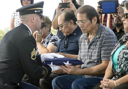 A member of the Joint Base San Antonio-Fort Sam Houston Honor Guard presents a flag to Alejandro Sandoval, one of Cpl. Frank Sandoval’s two sons, at the service at the Fort Sam Houston National Cemetery July 11.