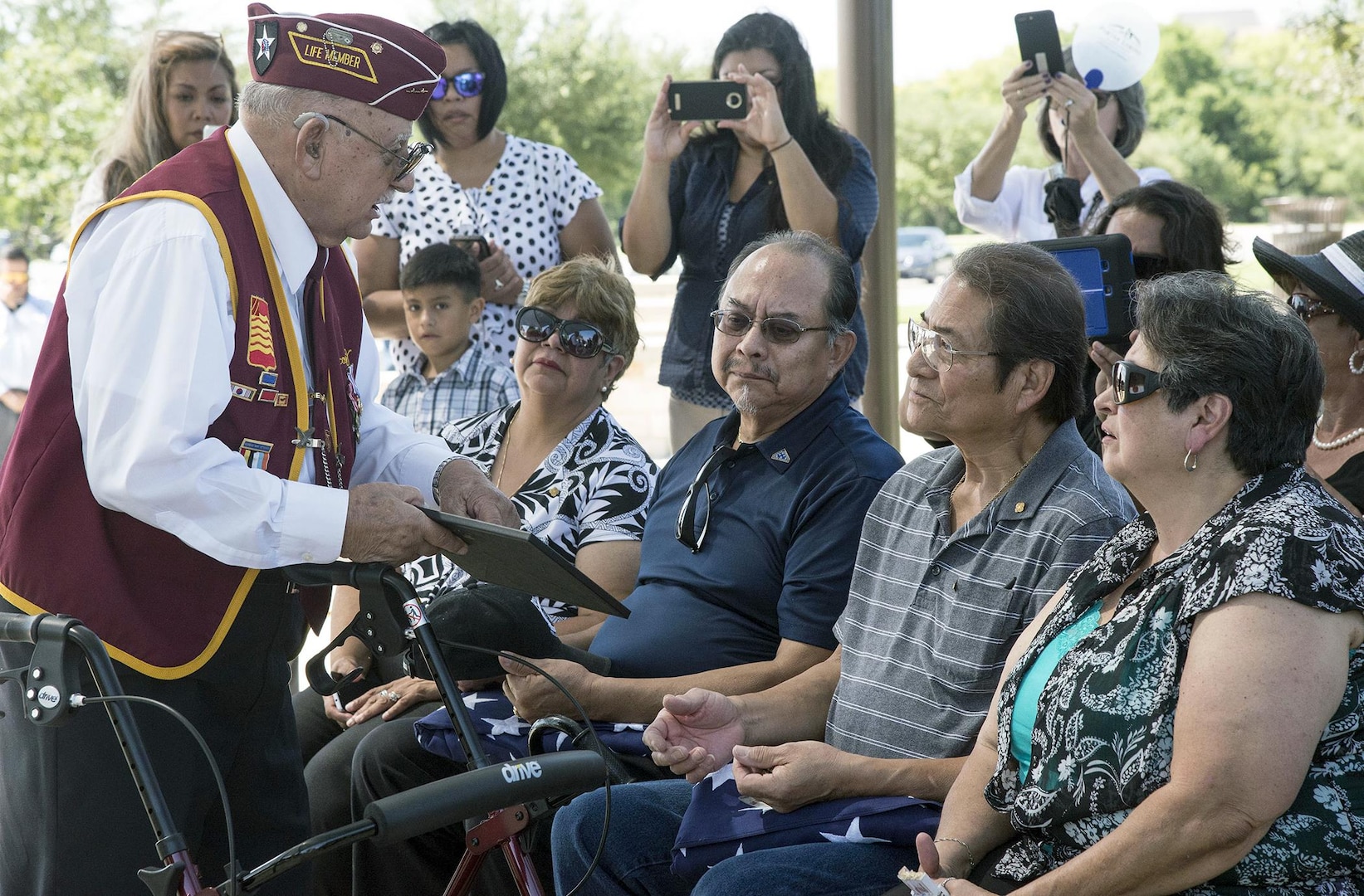 Oscar Cortez (left), a former Korean War POW who served in the same unit with Army Cpl. Frank Sandoval, presents a framed photo of the unit he and Sandoval served in while they were in action to Sandoval’s sons, Frank Jr. and Alejandro, July 11. Cortez, 85, said the photo was taken three to four days before their unit was captured.