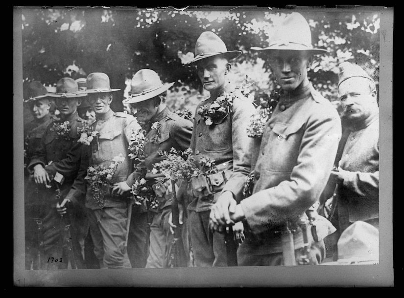 U.S. soldiers at the Picpus cemetery in Paris, where the Marquis de Lafayette is buried, are covered in flowers during a Bastille Day celebration in France, circa 1917-1920. Library of Congress photo