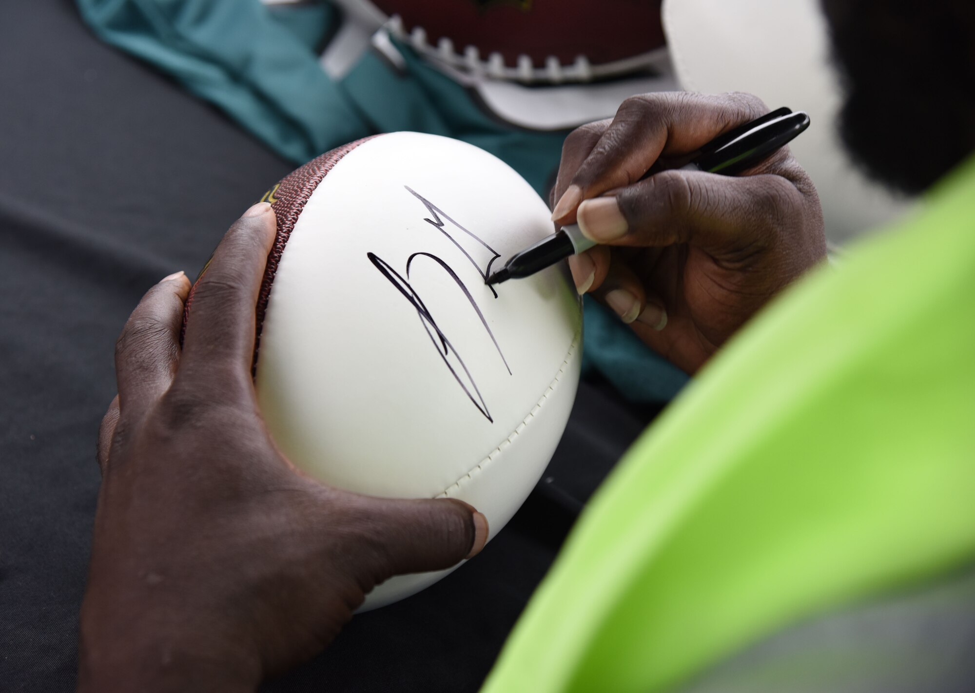 LeGarrette Blount, Philadelphia Eagles National Football League running back, signs a football during the P&G LeGarrette Blount 7x7 Football Championship July 8, 2017, on Keesler Air Force Base, Miss. Blount hosted the two-day camp consisting of 10 flag football teams from Keesler and the local community to promote the importance of living an active and healthy lifestyle. (U.S. Air Force photo by Kemberly Groue)