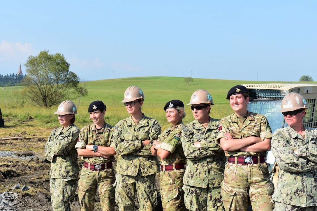 Sappers from the British Army Reserve's Royal Monmouthshire Royal Engineers (Militia) and Seabees from the Naval Mobile Construction Battalion 1 pose in front of engineering equipment at the Joint National Training Center, Cincu, Romania, for International Women in Engineering Day, June 23, 2017. The service members were participating in exercise Resolute Castle. Army photo by Capt. Colin Cutler